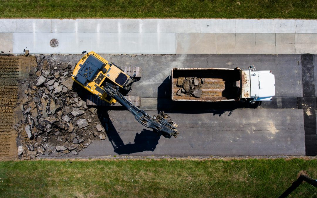 aerial photography of yellow heavy equipment beside white dump truck at daytime